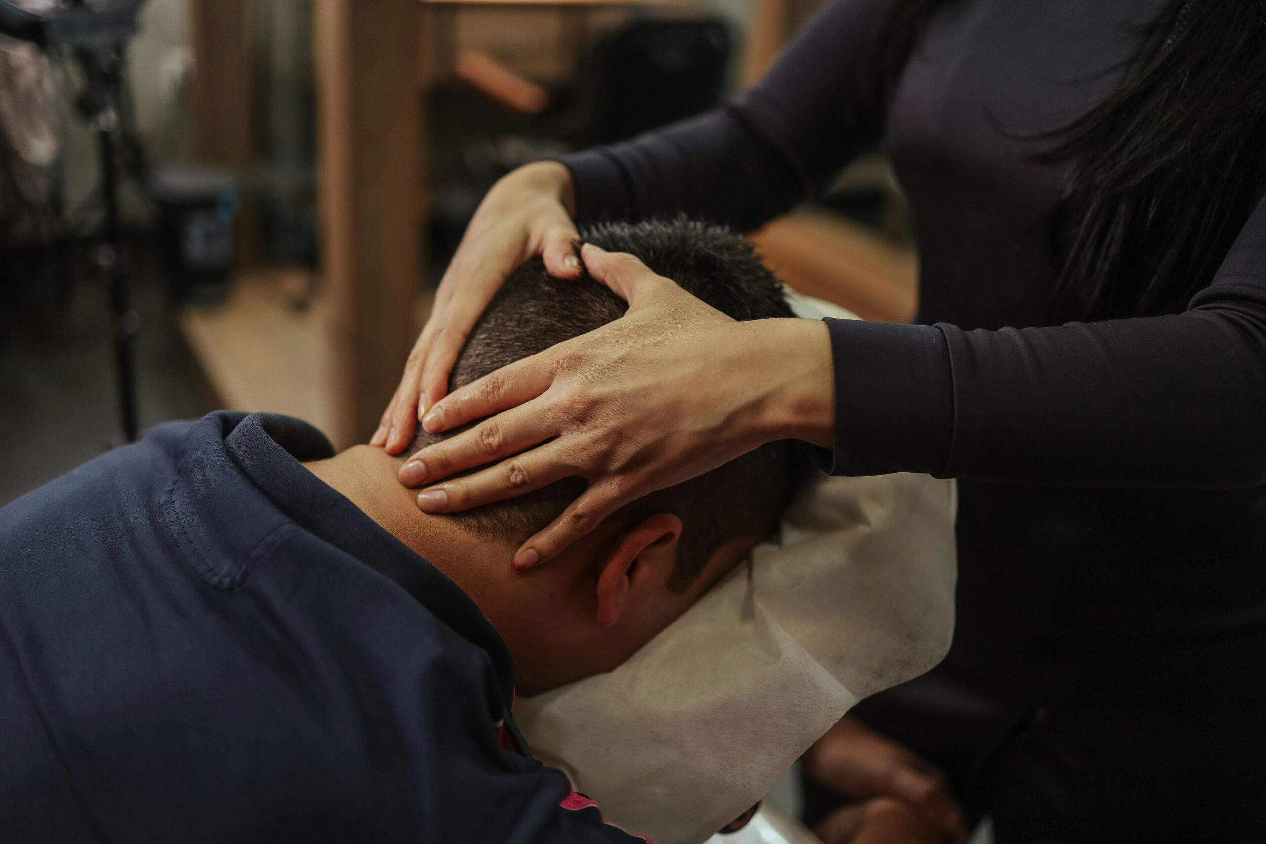 Person receiving a head and neck massage with gentle pressure applied by a therapist in a calm indoor spa setting